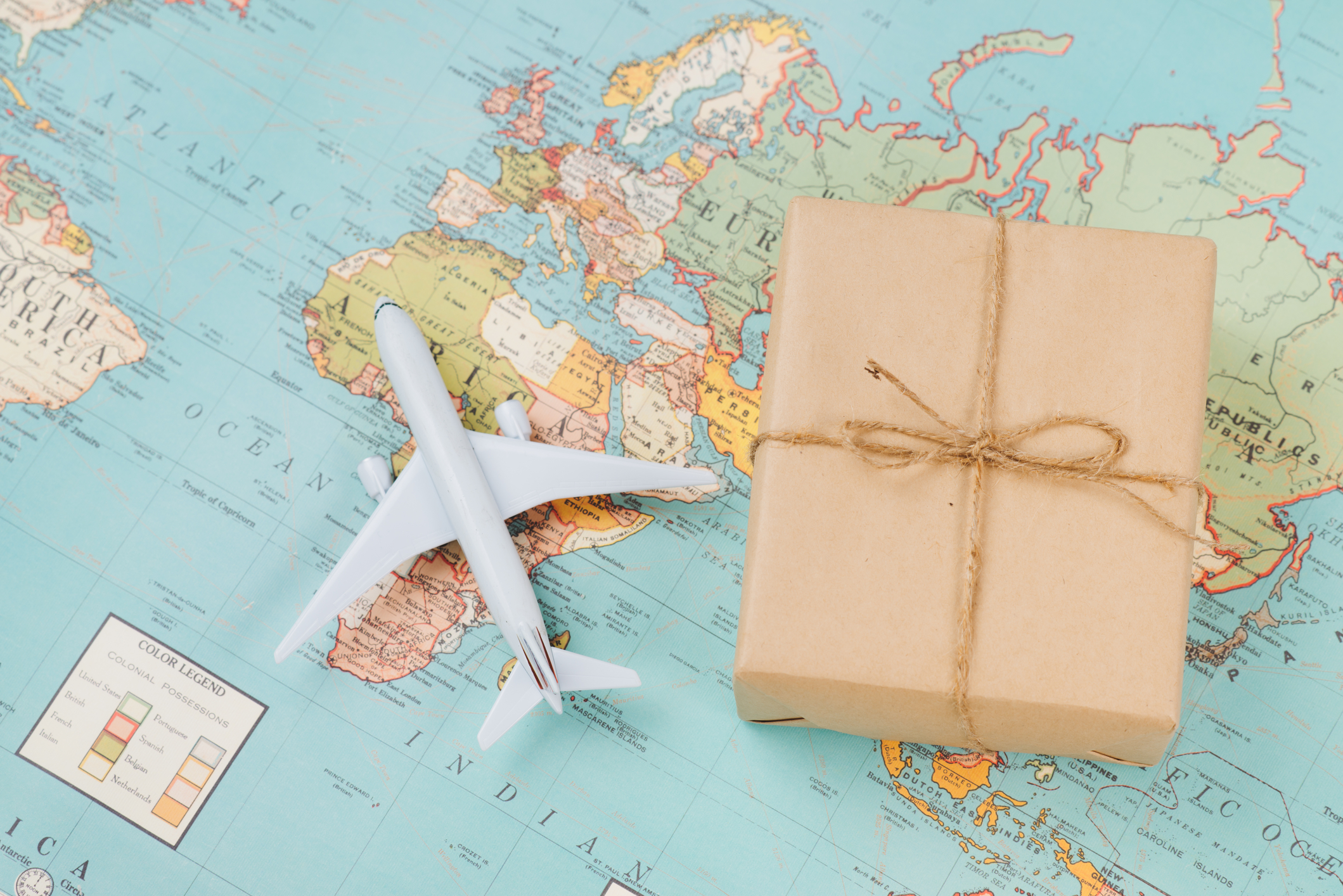 toy plane sitting on world map next to brown package