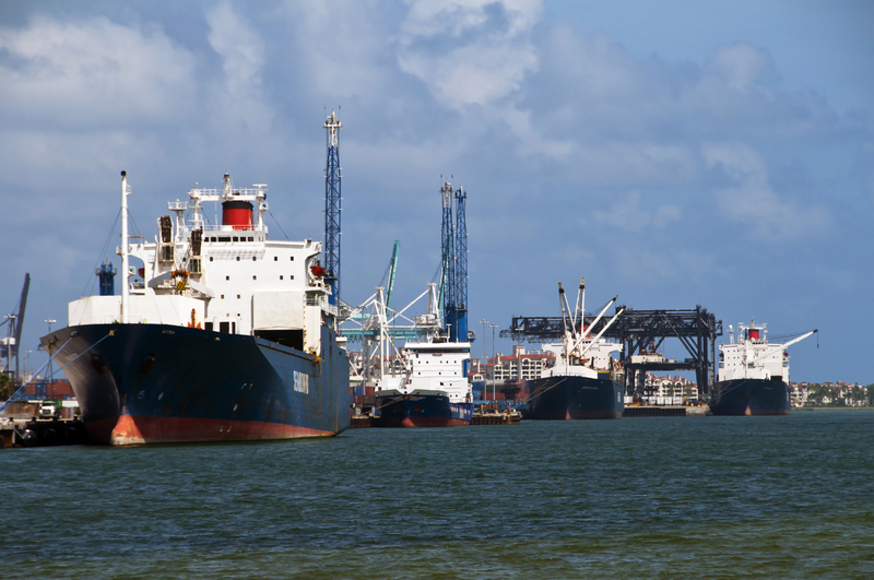 A row of Cargo ships getting loaded at a busy port