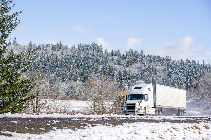 White semi-truck driving along snowy highway