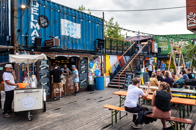 People sitting outside shipping container converted to a food truck